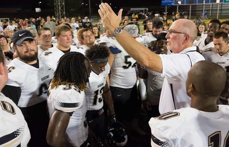 players gathered around football coach