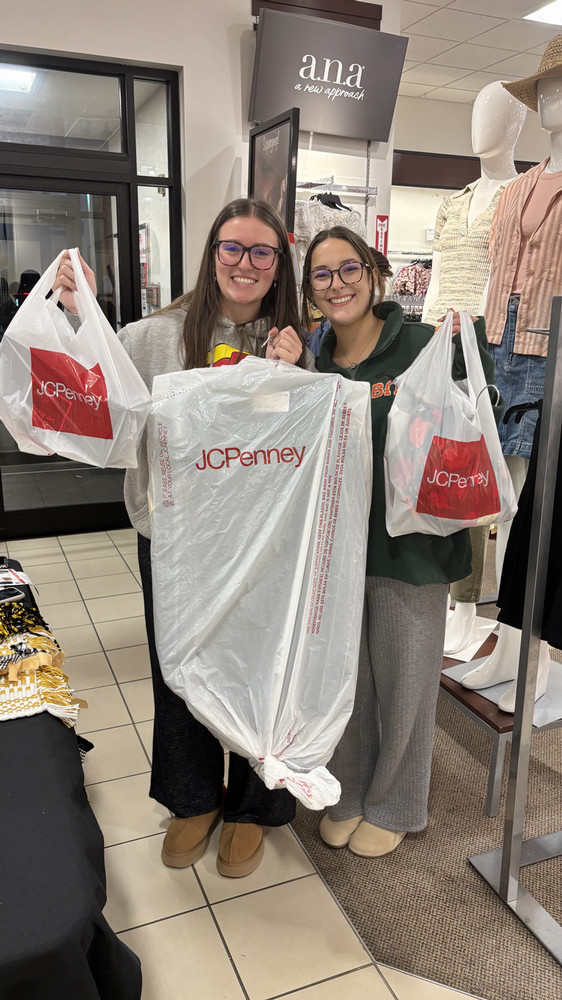 Two smiling female Harding students pose with shopping bags from JCPenney following Bisons Suit Up event