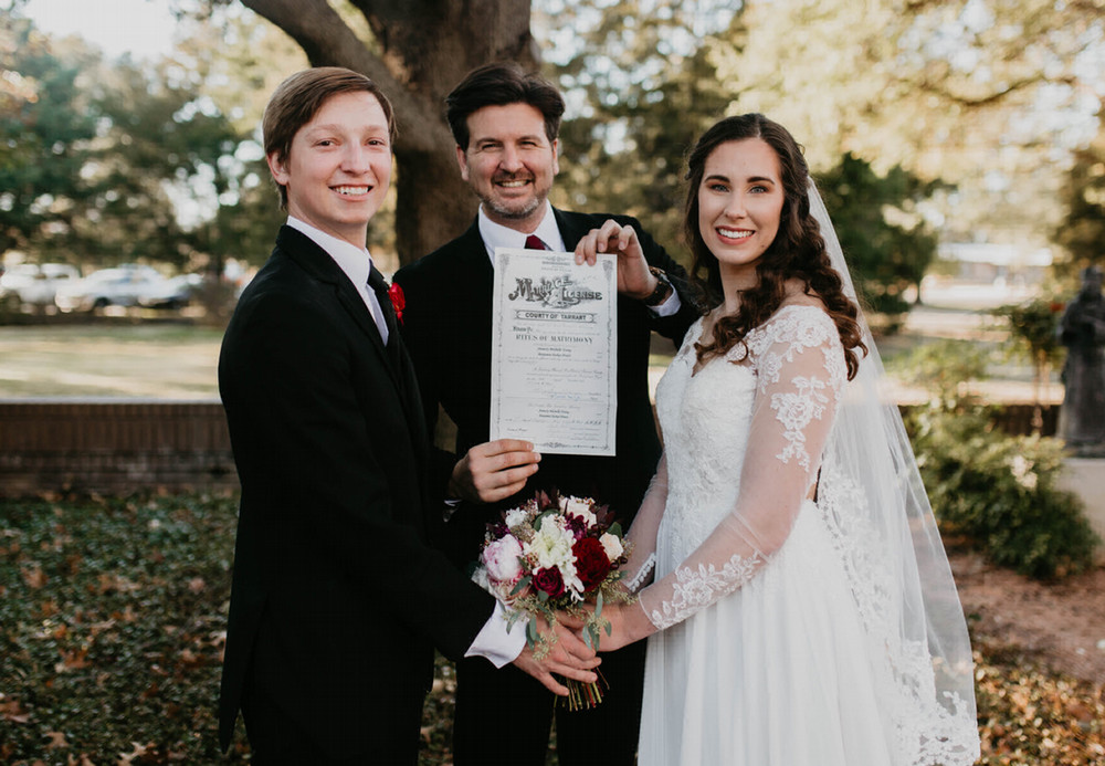 Mac Sandlin holds the marriage license after performing the ceremony for Parker and Annesly Young Pruitt's wedding