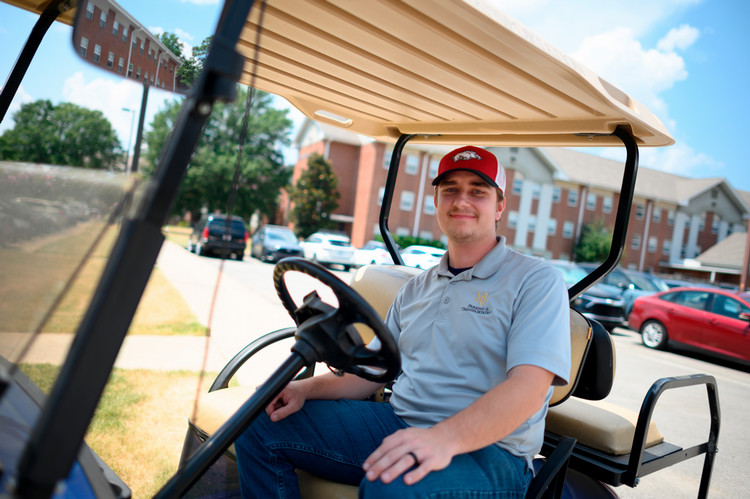 Logan Wolfe smiles on a University golf cart 