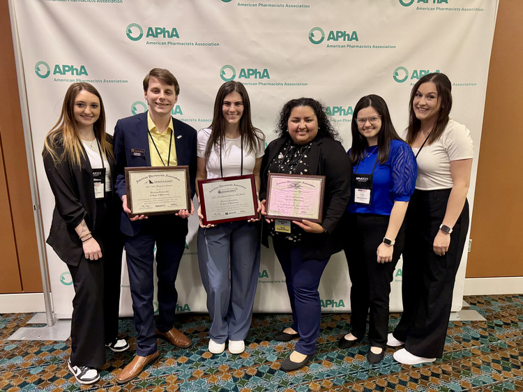 Five students pose with framed certificate at the American Pharamacists Association conference