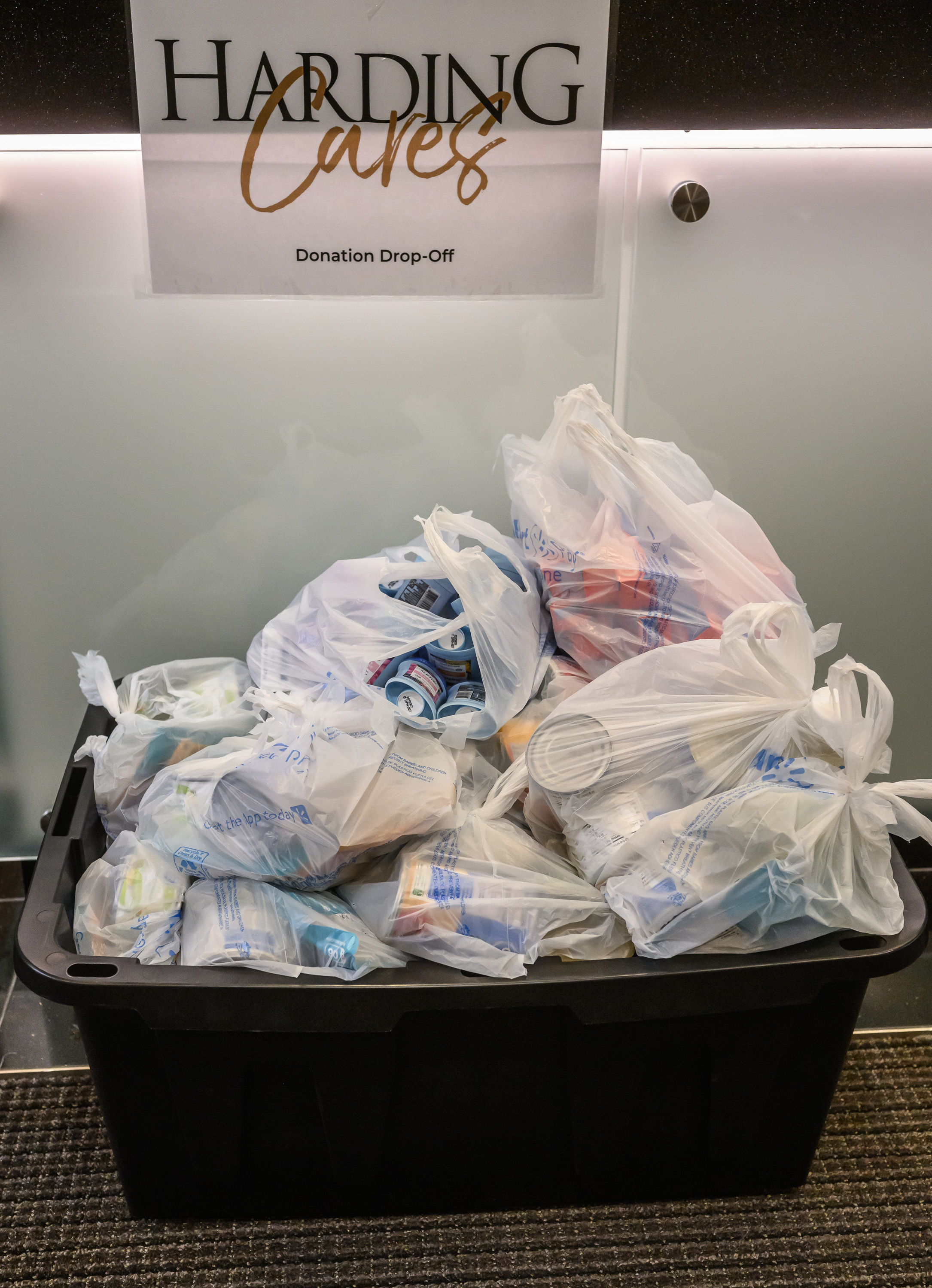 A pile of food items in plastic sacks inside a Harding Cares donation bin