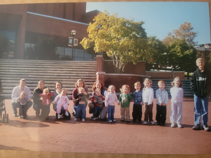 Jennifer Kennedy, her friends, and their total of twelve children are shown standing in front of the Benson Auditorium.