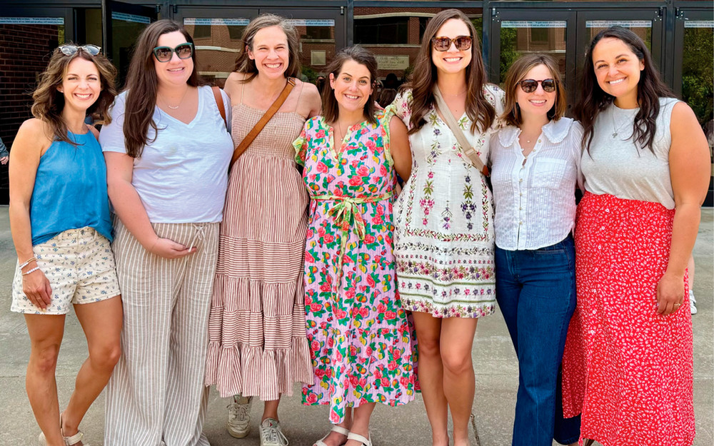 Picture is Liz McDowell and her friend group smiling in front of the Benson Auditorium