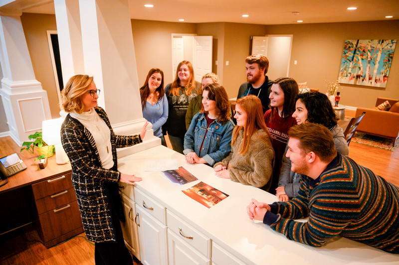 Amy Cox is shown talking to students in a home.